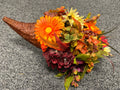Fall cornucopia with faux orange daisies, burgundy hydrangeas, and autumn foliage