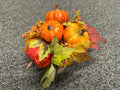 Faux pumpkin and gourd fall centerpiece with maple leaves and berry sprigs