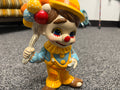 Vintage ceramic clown figurine holding balloon bouquet in yellow hat and blue outfit