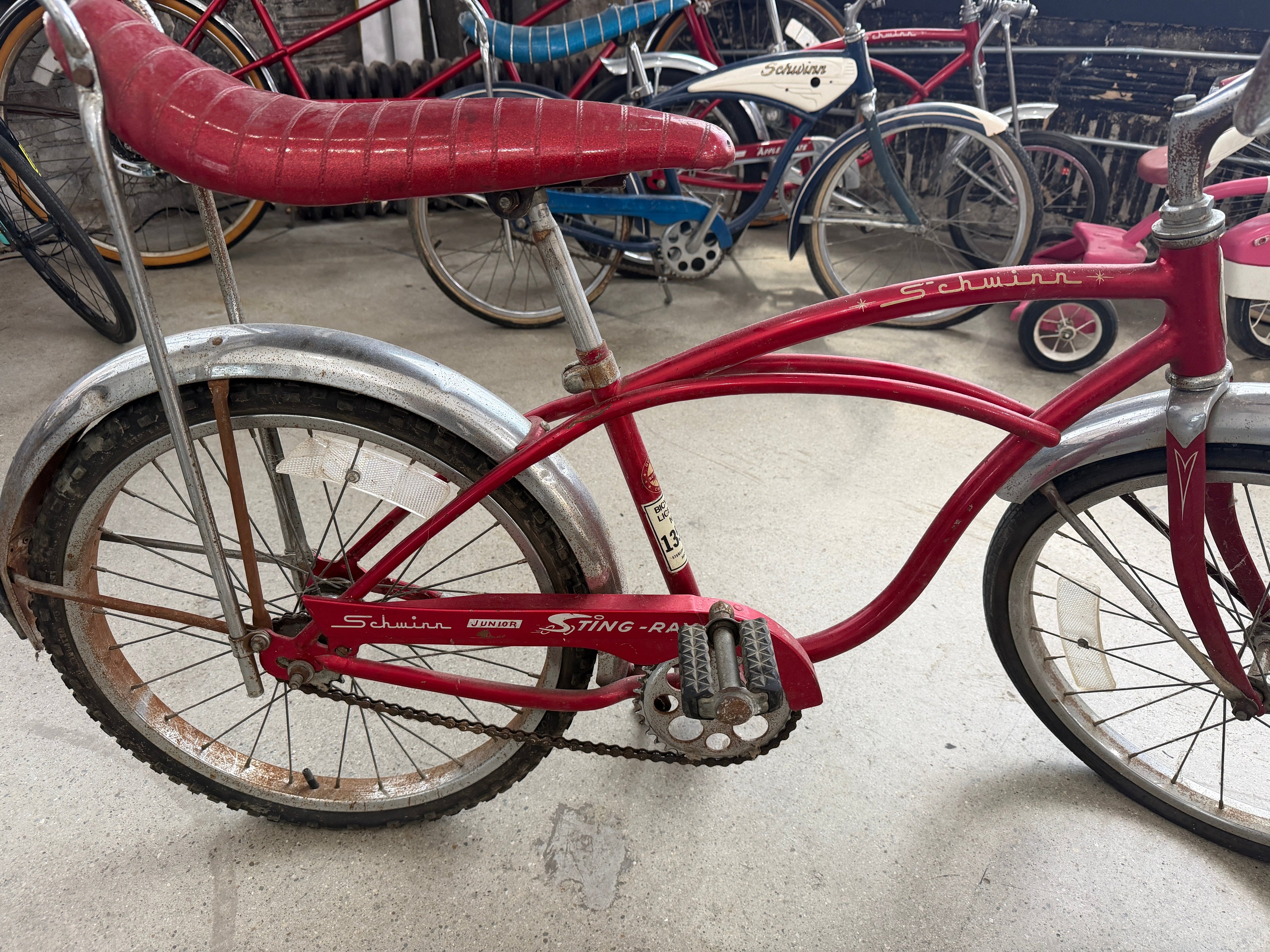 Early 1970s Schwinn Junior Sting-Ray bicycle in original Campus Red finish with chrome fenders, banana seat, and original chain guard graphics — full side profile at The Foundry in downtown Pontiac, Michigan