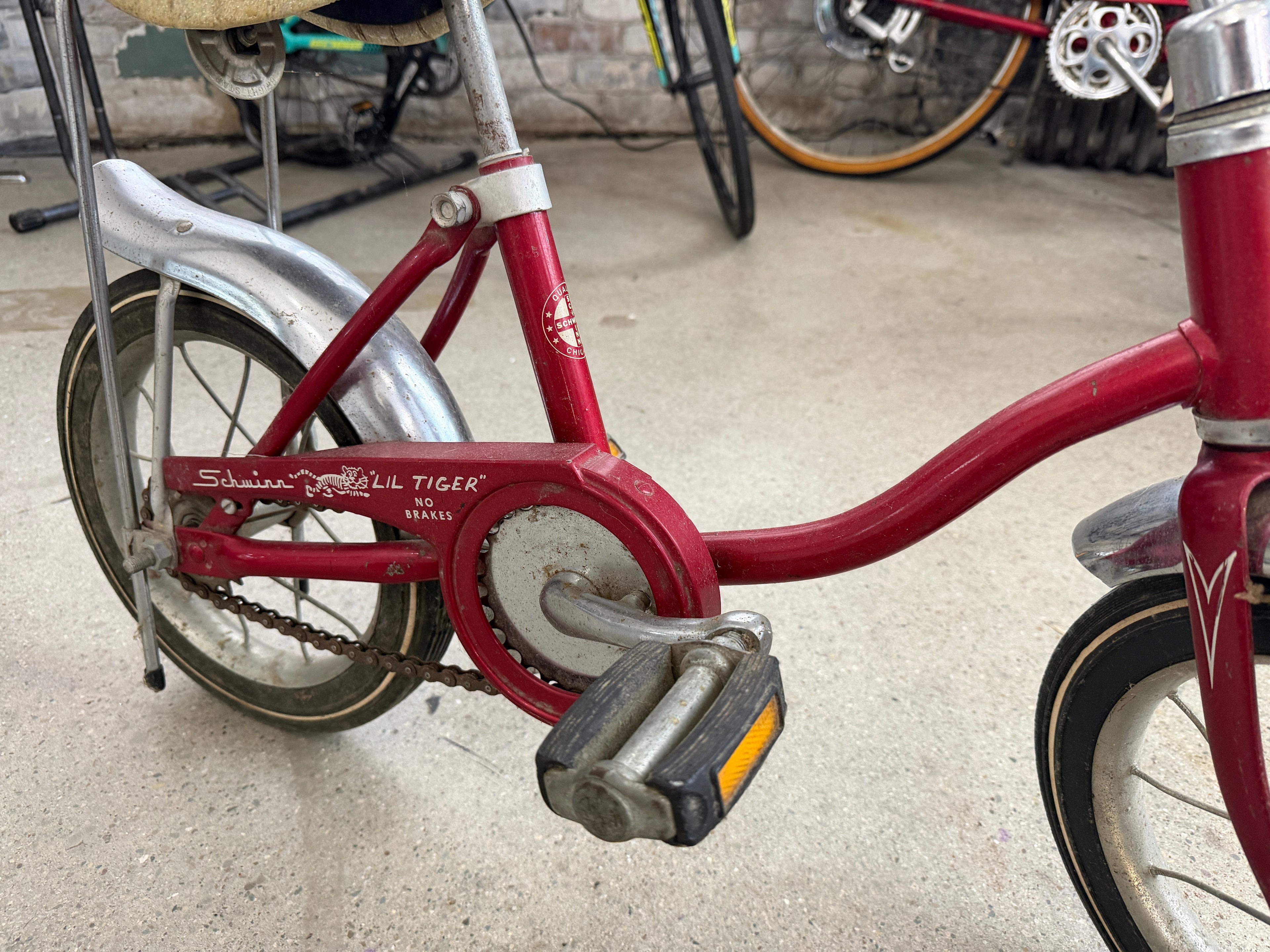 Vintage Schwinn Lil' Tiger children's bicycle in red showing original Lil' Tiger chain guard graphics, Schwinn script, chrome fender, and classic pedals — consignment display piece at The Foundry by History Loves Company in downtown Pontiac, Michigan