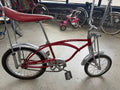 Vintage Schwinn Sting-Ray Apple Krate bicycle in red with banana seat, tall sissy bar, chrome fenders, springer-style front fork, and high-rise handlebars — full side profile at The Foundry by History Loves Company in downtown Pontiac, Michigan