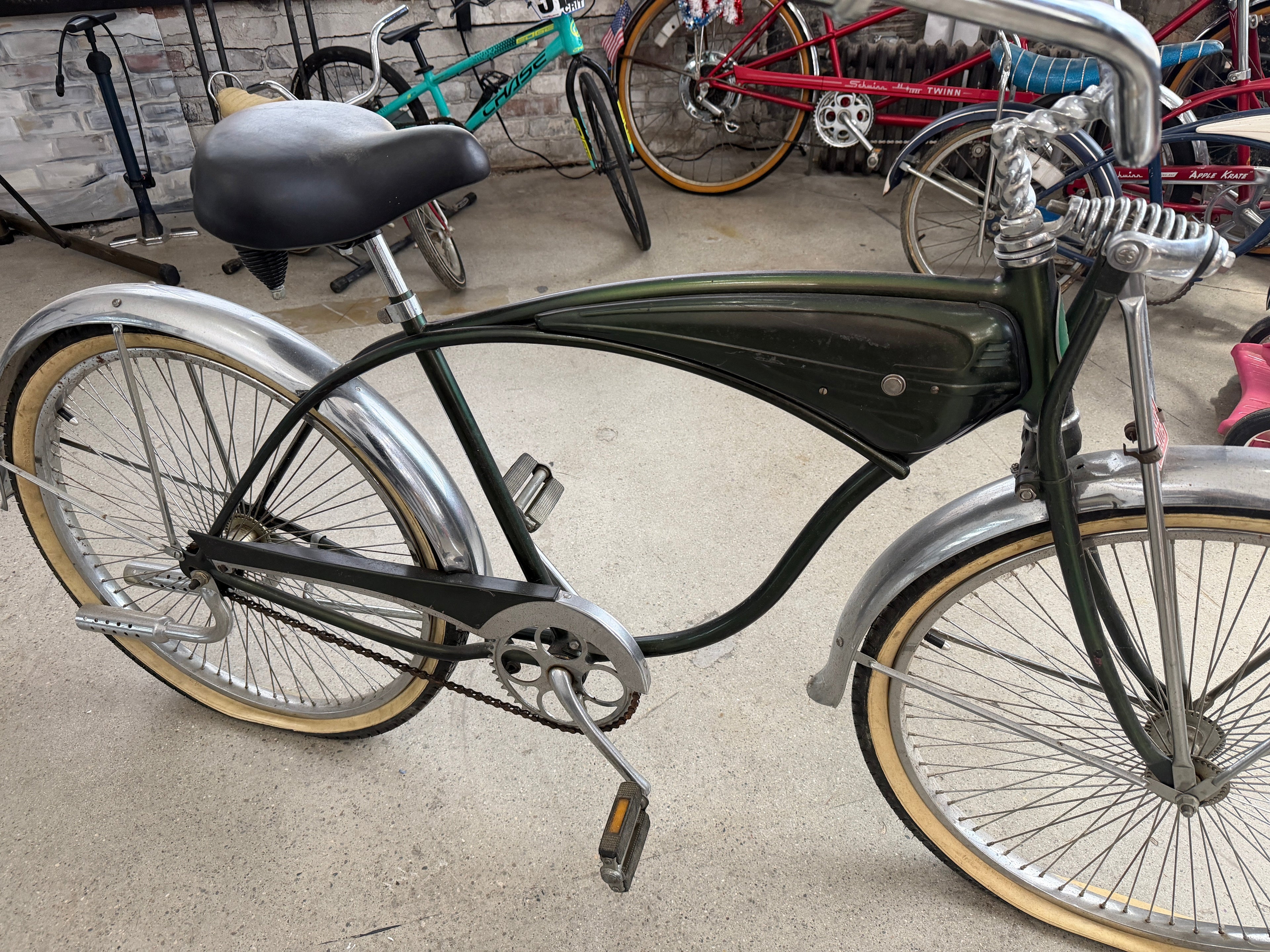 Vintage Schwinn tank cruiser full profile, forest green frame, chrome fenders, whitewall tires, springer fork
