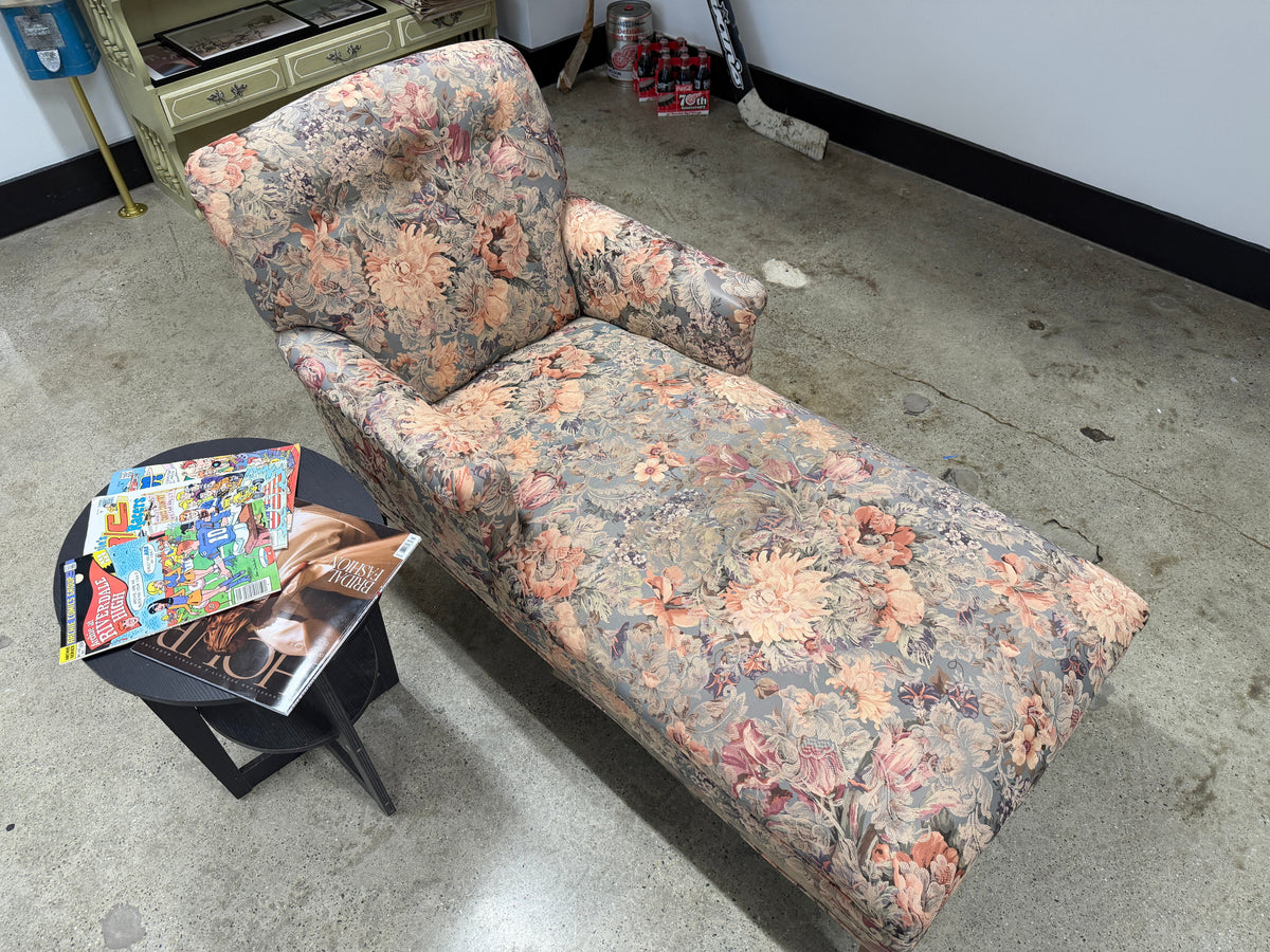 Floral upholstered chaise lounge with extended lounge seating, raised back, rolled arm, and soft vintage-inspired floral tapestry pattern in pink, peach, and sage — on consignment at The Foundry by History Loves Company in downtown Pontiac, Michigan
