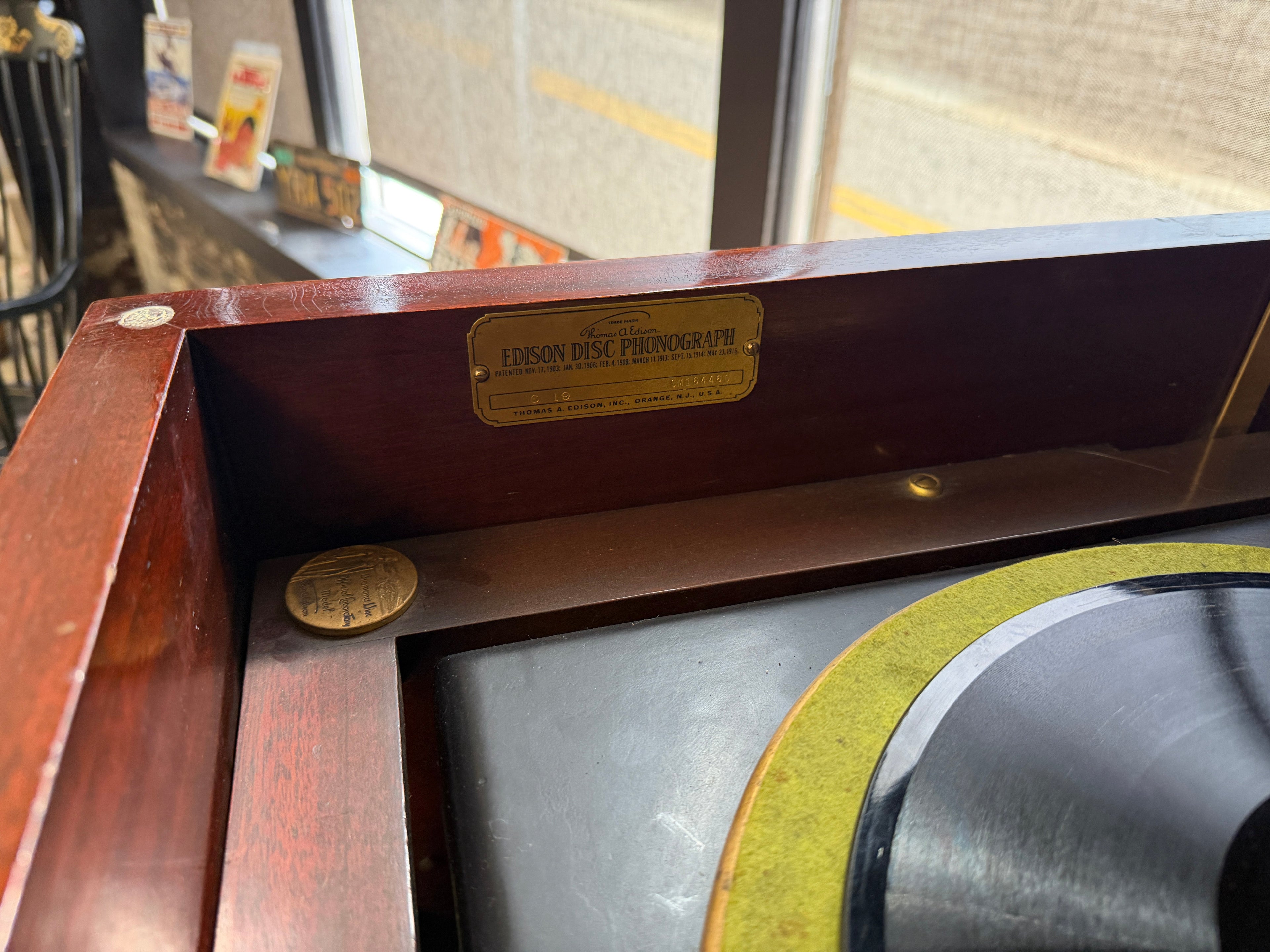 Close-up of Thomas A. Edison Disc Phonograph identification plate inside cabinet lid showing model C-19, serial number SM161446C, patented dates from 1903–1916, Thomas A. Edison Inc., Orange, NJ, USA