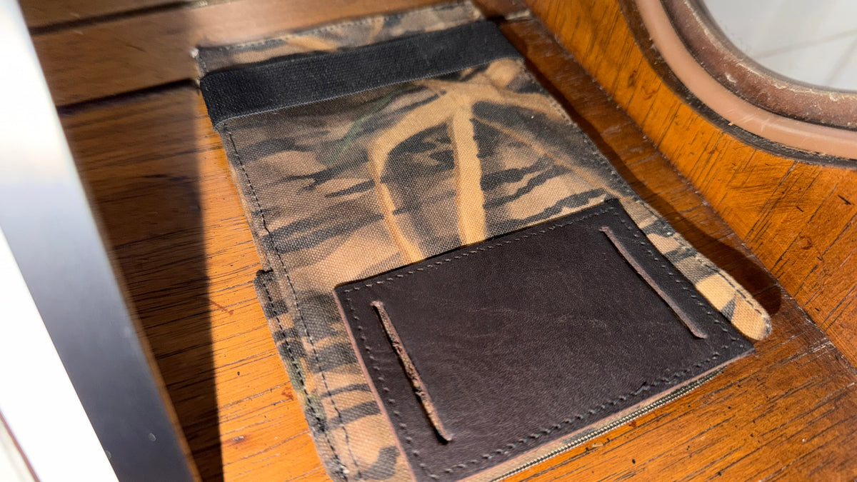 The Forge Hip Pack in camo canvas with brown front pocket, Pontiac Built by The Foundry, on wooden surface