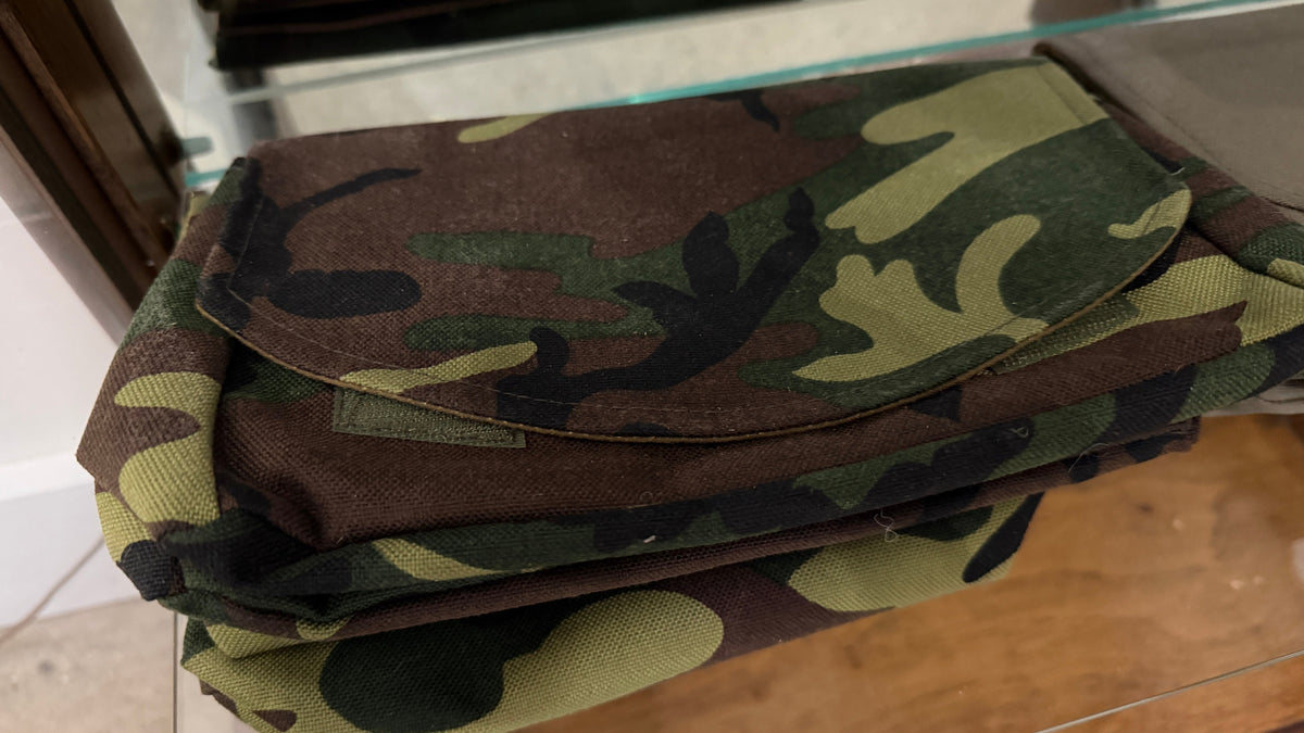 The Market Pouch in woodland camo canvas, stack of three, Pontiac Built by The Foundry on glass shelf