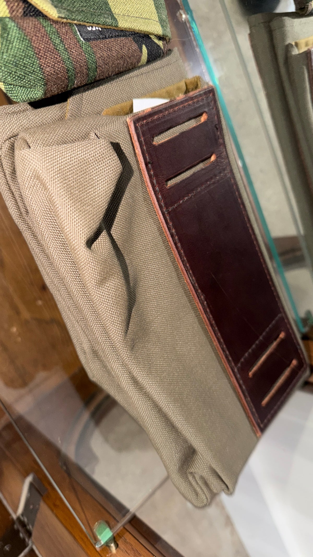 The Market Pouch in tan khaki canvas with dark brown leather card slot panel, Pontiac Built by The Foundry on glass shelf