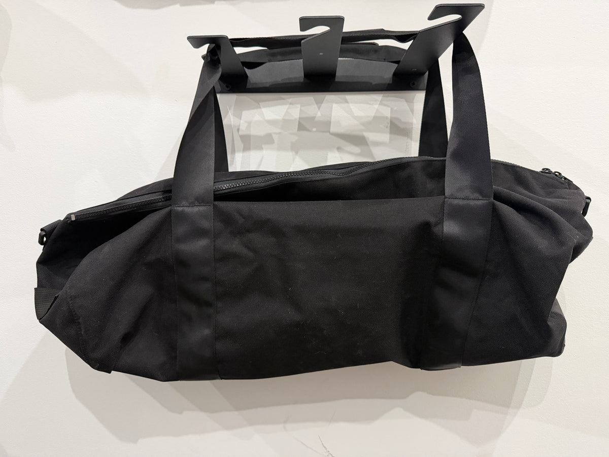 The Weekender Duffle in all black by The Foundry, made in Pontiac Michigan, top zip and side pocket detail