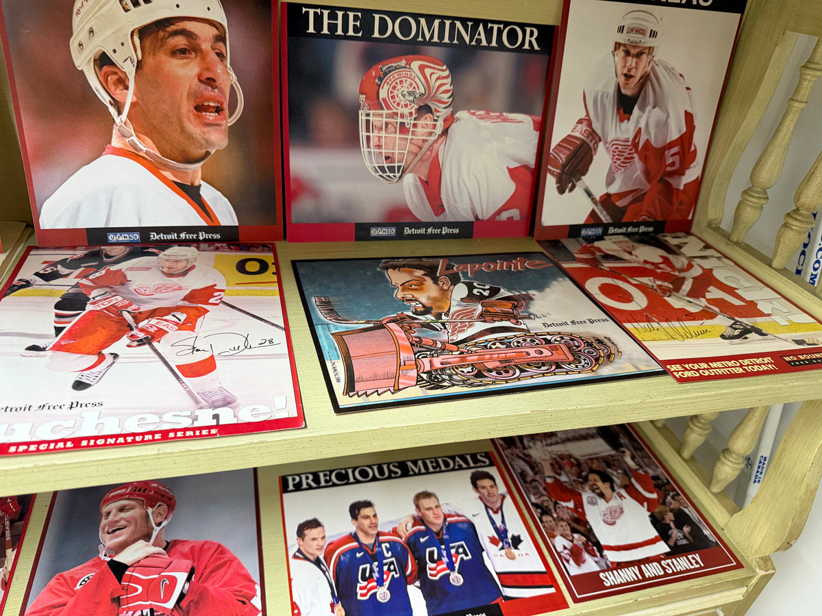 Detroit Free Press Red Wings collector prints on shelf including The Dominator Hasek, Yzerman, Lidstrom, Shanahan, Precious Medals and more