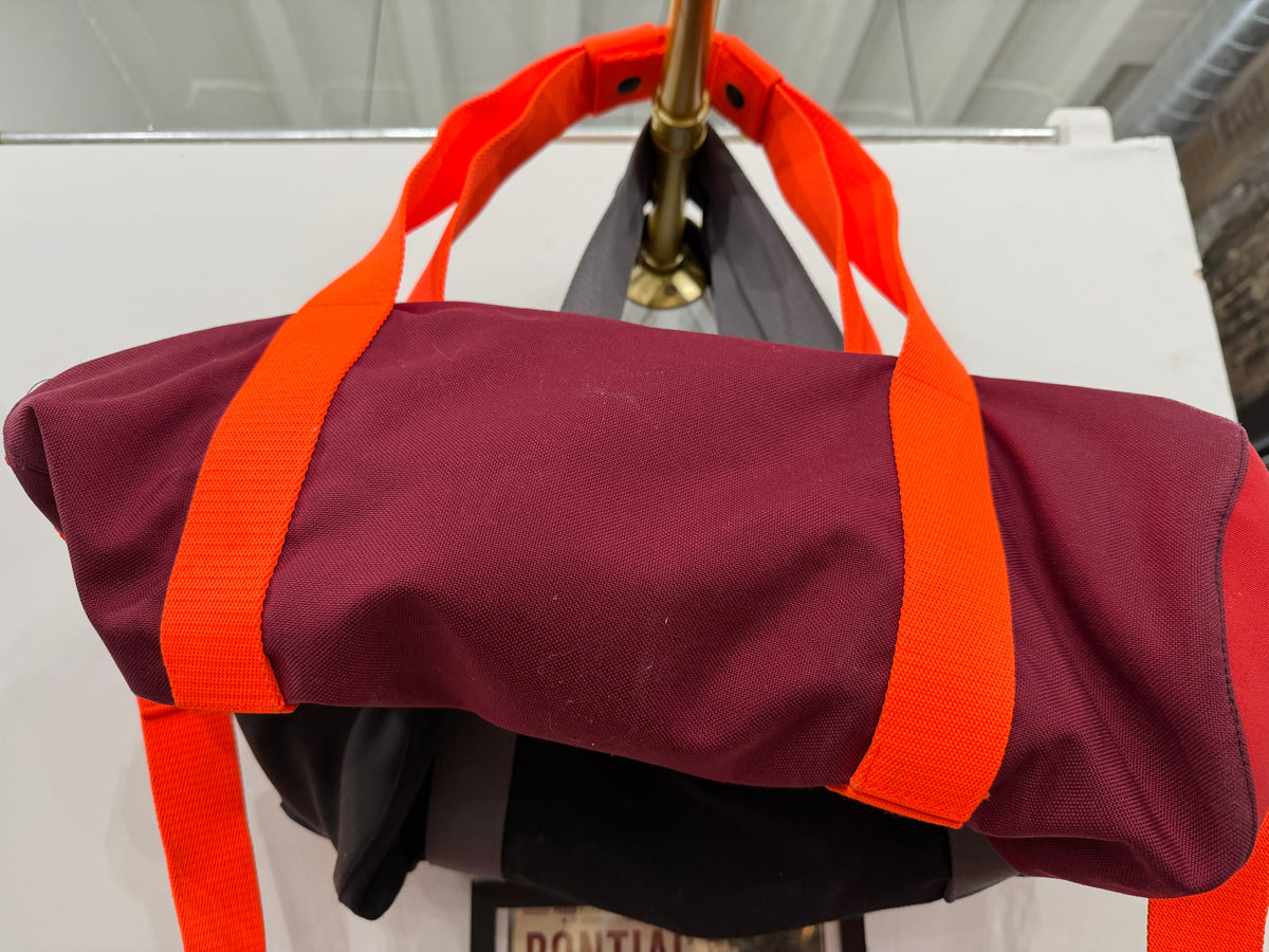 The Overnight Duffle in maroon with orange straps by The Foundry, made in Pontiac Michigan
