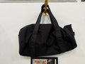 The Overnight Duffle in all black by The Foundry, made in Pontiac Michigan, hanging on brass rack