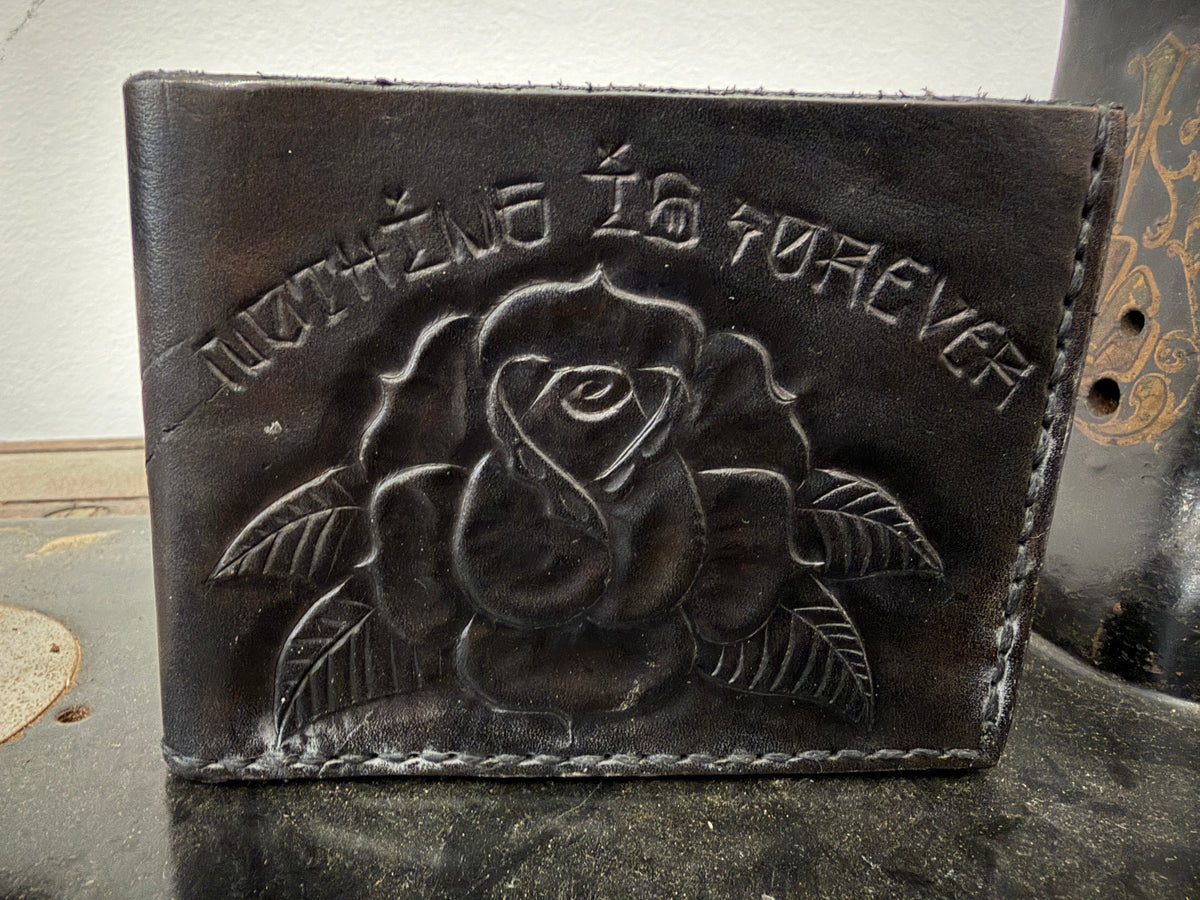 The Tradesman Wallet in jet black leather, hand-tooled rose with Nothing Is Forever in old English lettering, cream saddle stitch