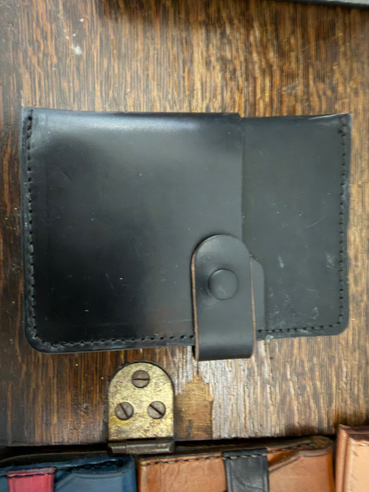 The Wayfarer Passport Wallet in jet black full-grain leather, snap closure tab, hand-stitched perimeter, open bifold view, Pontiac Built by The Foundry