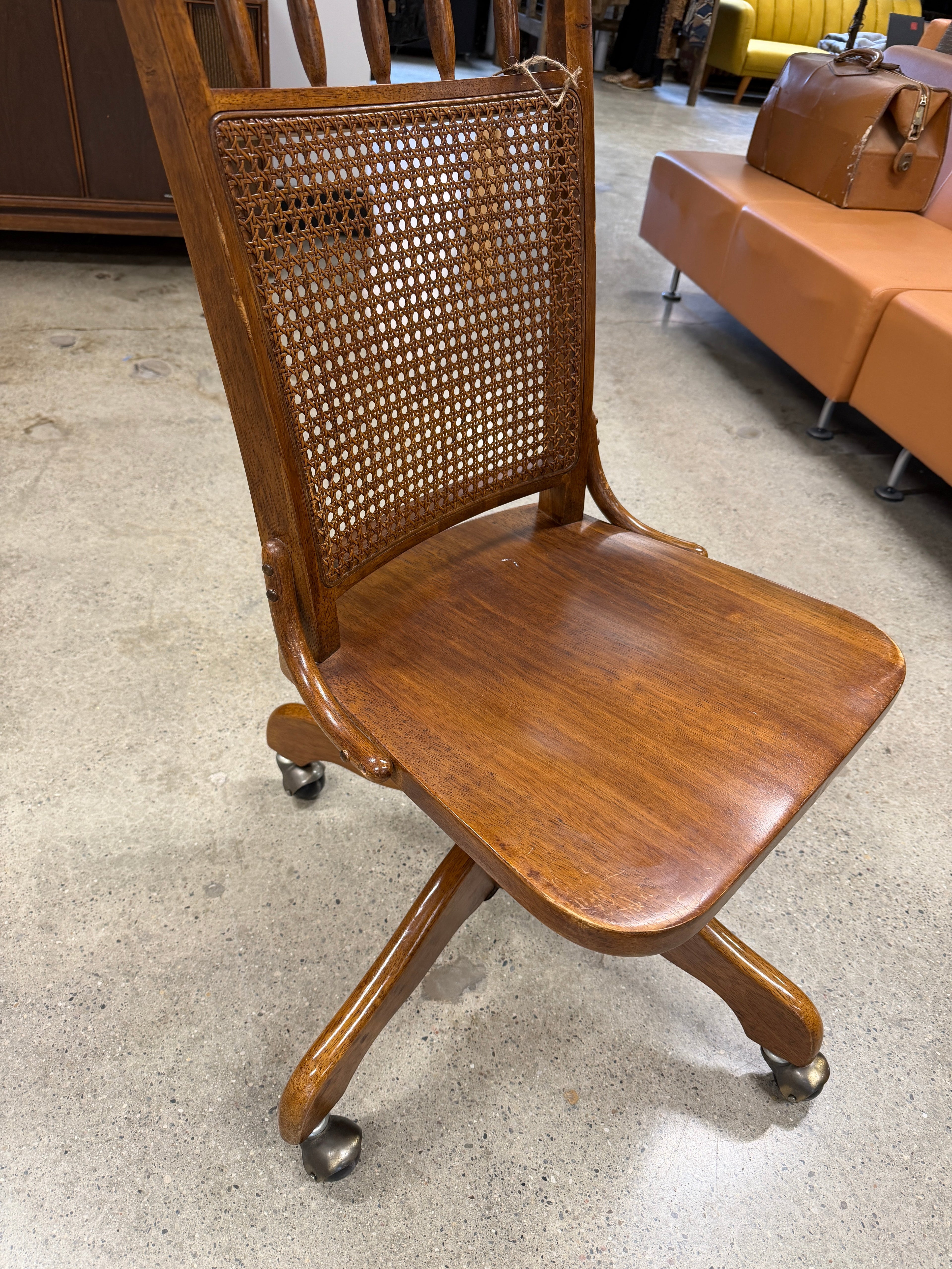 Antique oak rolling desk chair with woven cane back panel, cabriole legs, brass ball casters, smooth oak seat with rounded corners