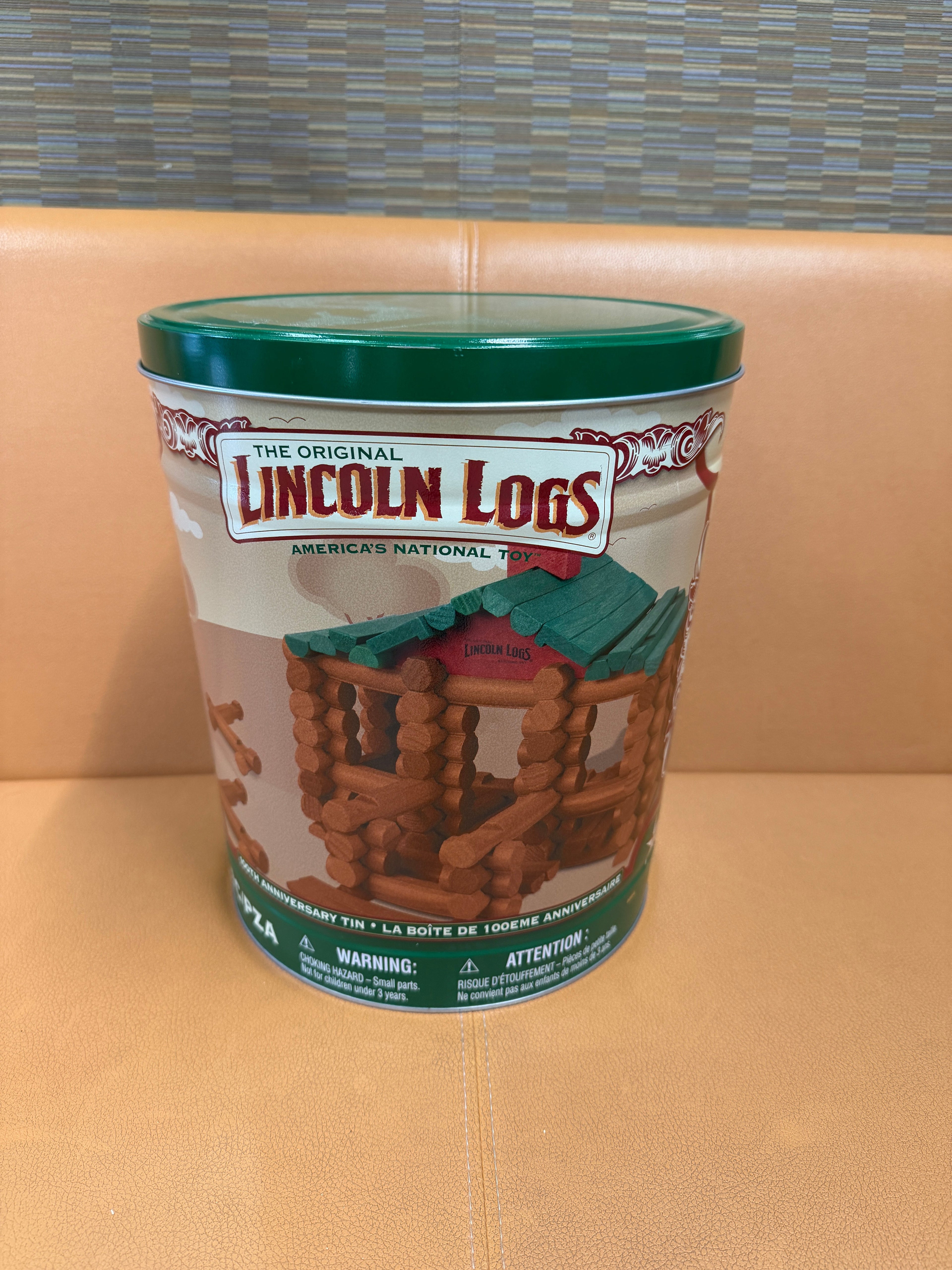 Lincoln Logs 100th Anniversary collector's tin with green lid, illustrated label showing log cabin, America's National Toy centennial edition