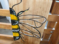 Hand-drawn bumblebee with yellow and black body and translucent wings on natural wood panel by Renee Reese