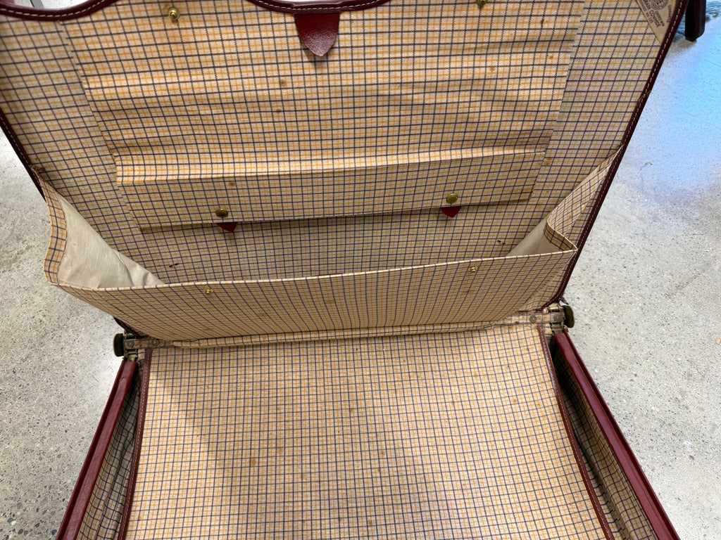 Interior of vintage leather attaché showing plaid fabric lining and multiple pockets