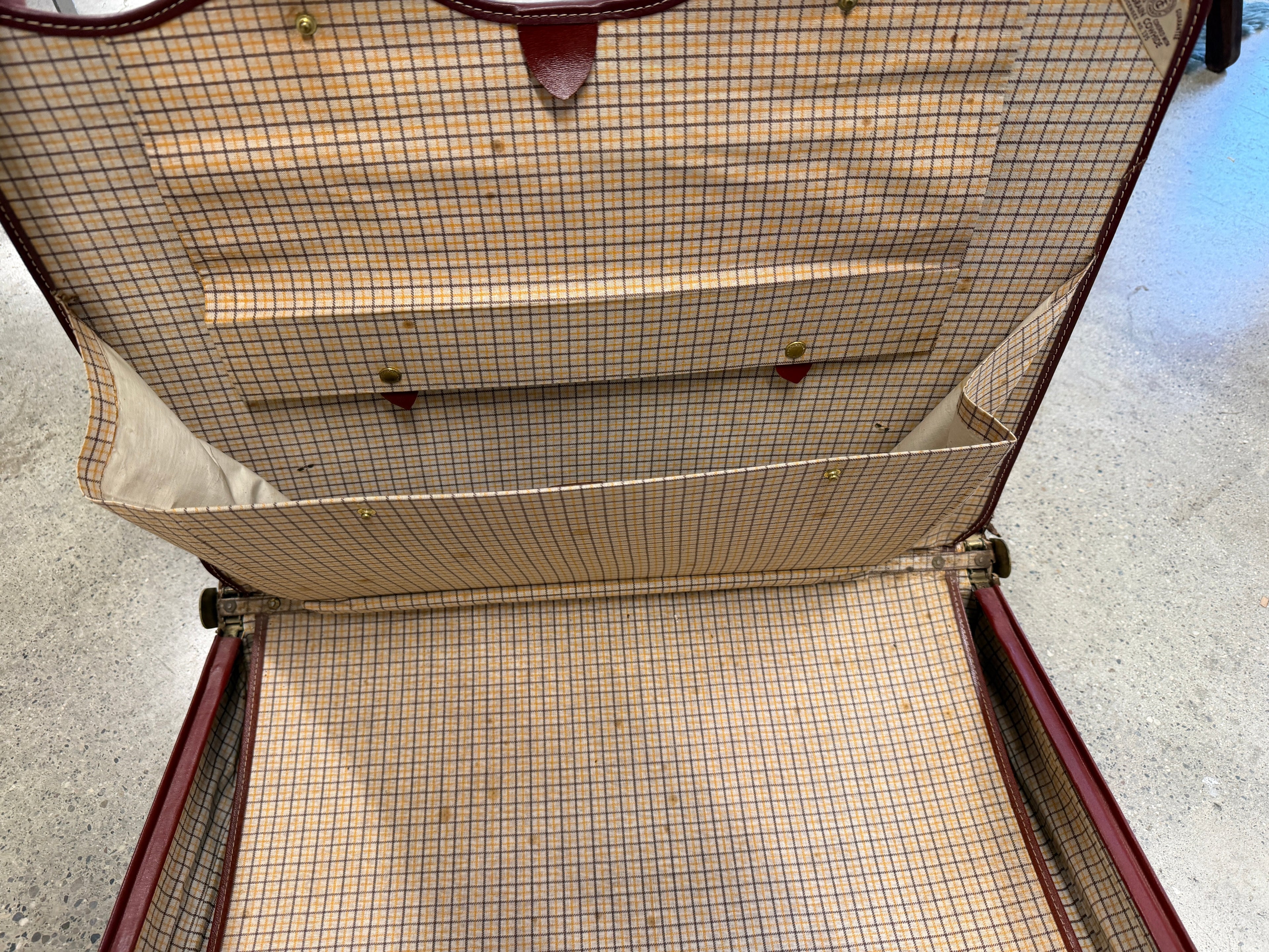 Interior of vintage leather attaché showing plaid fabric lining and multiple pockets