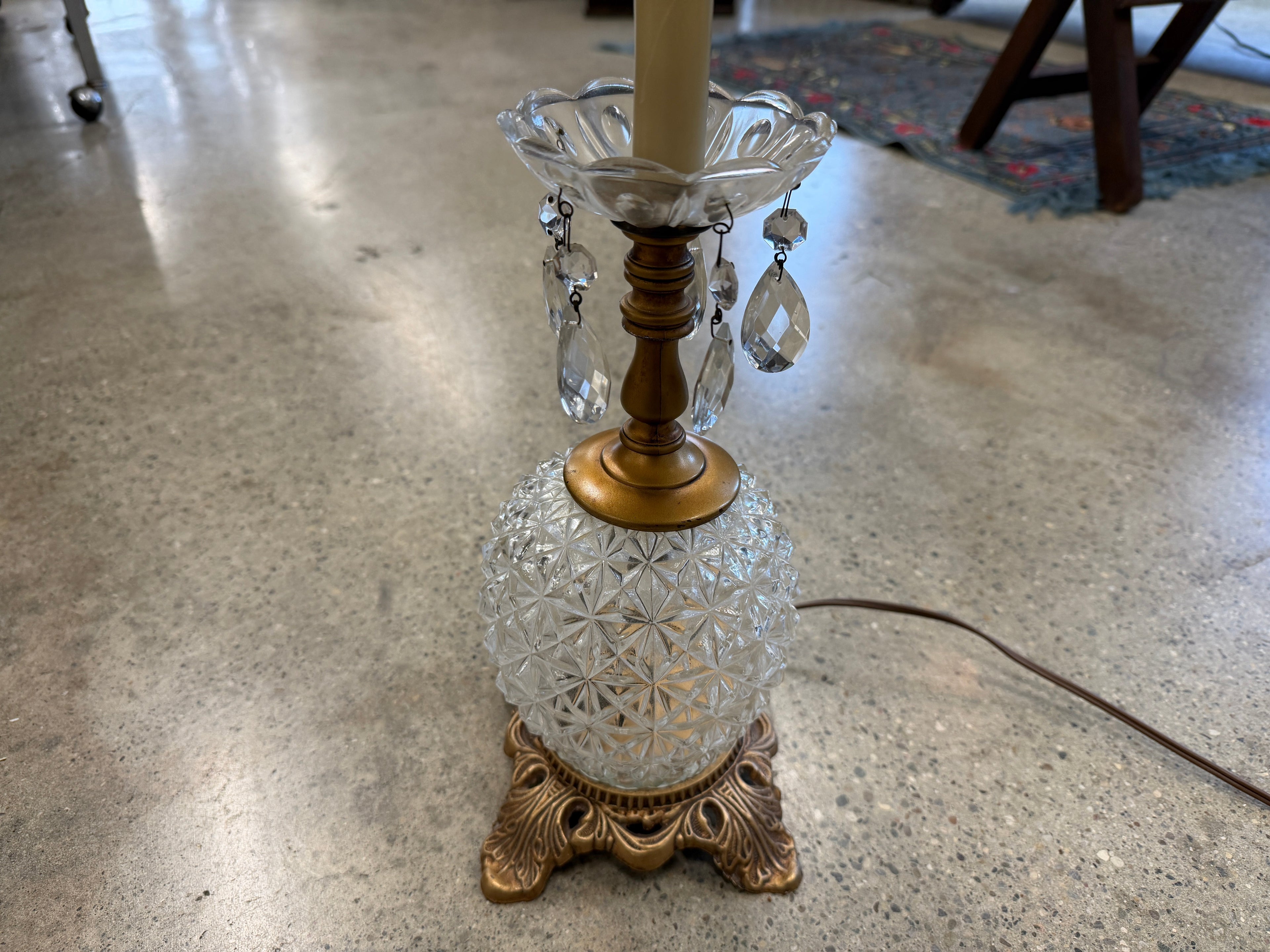 Close-up of cut crystal globe base with hanging prisms and ornate brass footed base