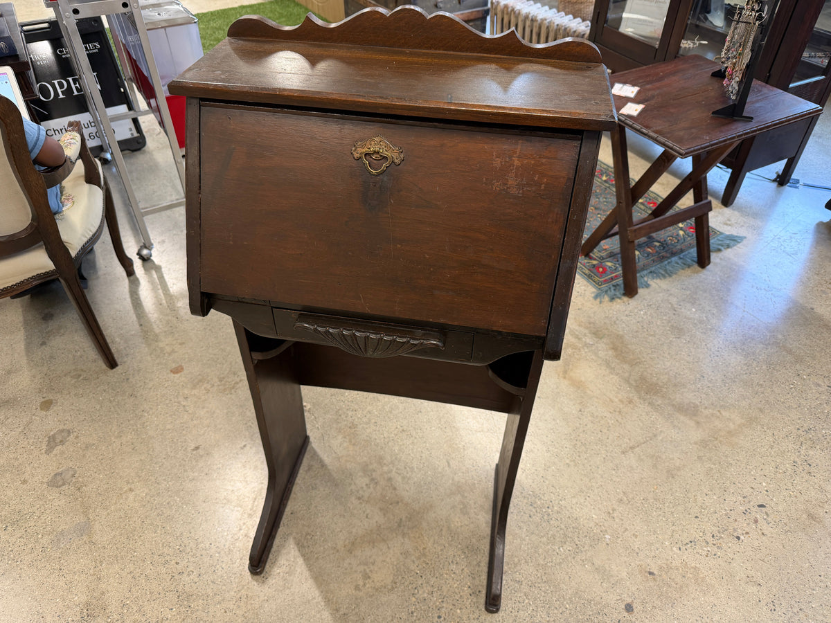 Antique drop-front secretary desk with scalloped gallery, brass ring pull, and carved fan apron