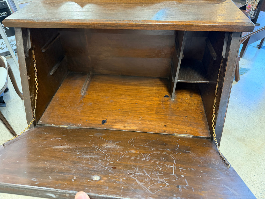 Interior of antique secretary desk showing chain-supported writing surface and interior cubbies