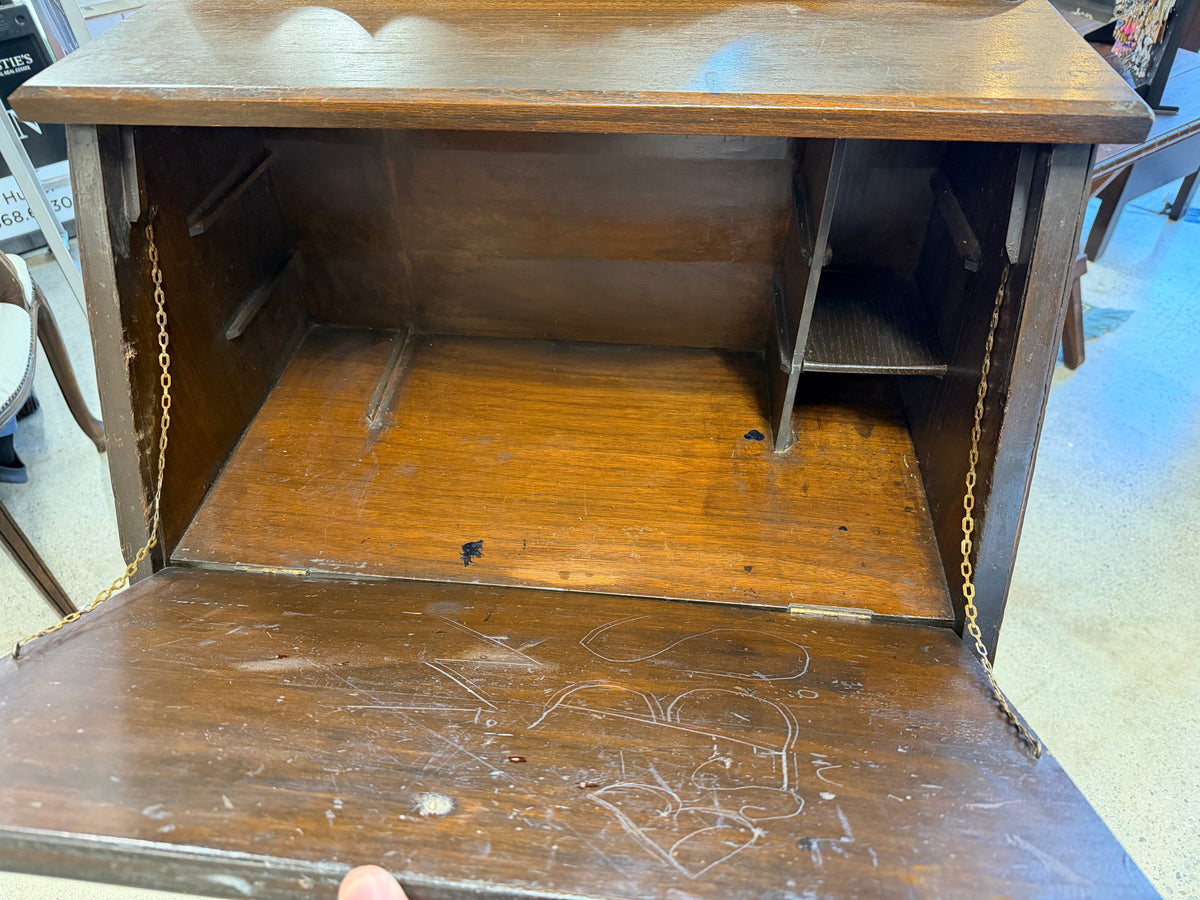Interior of antique secretary desk showing chain-supported writing surface and interior cubbies