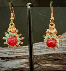 Handmade copper burst earrings by Sweet Sinister — red coral center with copper wire sunburst frame